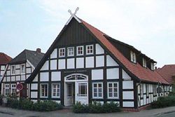 Fachwerkhaus mit rotem Dach und weißen Rahmen in ruhiger Umgebung.